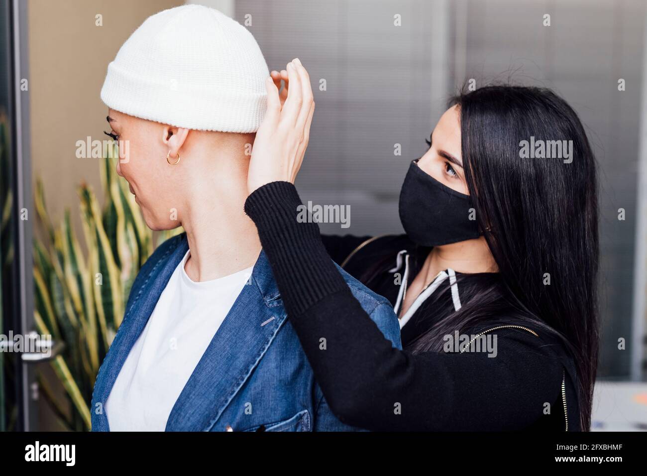Une femme dans un masque de visage aidant une femme d'affaires portant un chapeau en tricot au bureau Banque D'Images