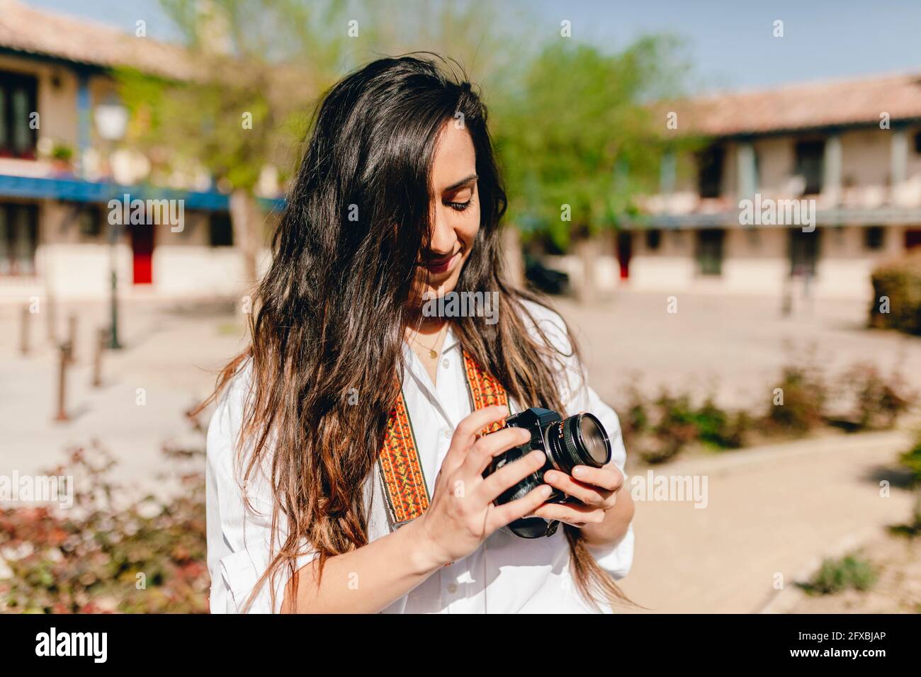 Une femme souriante tenant un appareil photo le jour du soleil Banque D'Images