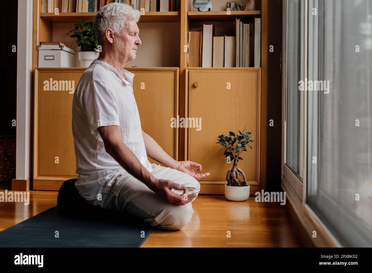 Homme pratiquant le yoga en position lotus à la maison Banque D'Images