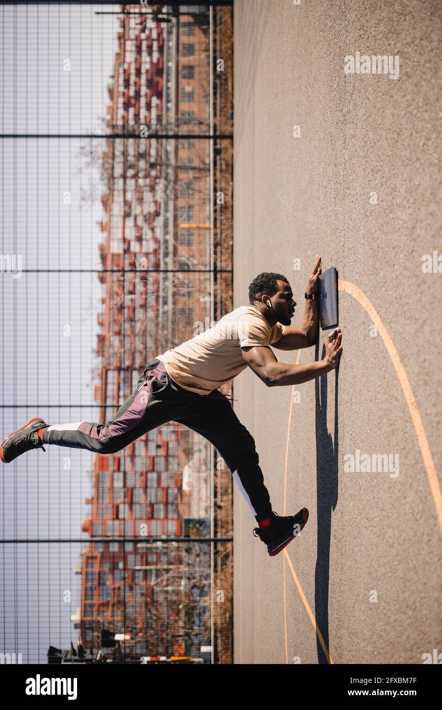 Jeune homme regardant une tablette numérique tout en faisant des acrobates sur un terrain de sport Banque D'Images