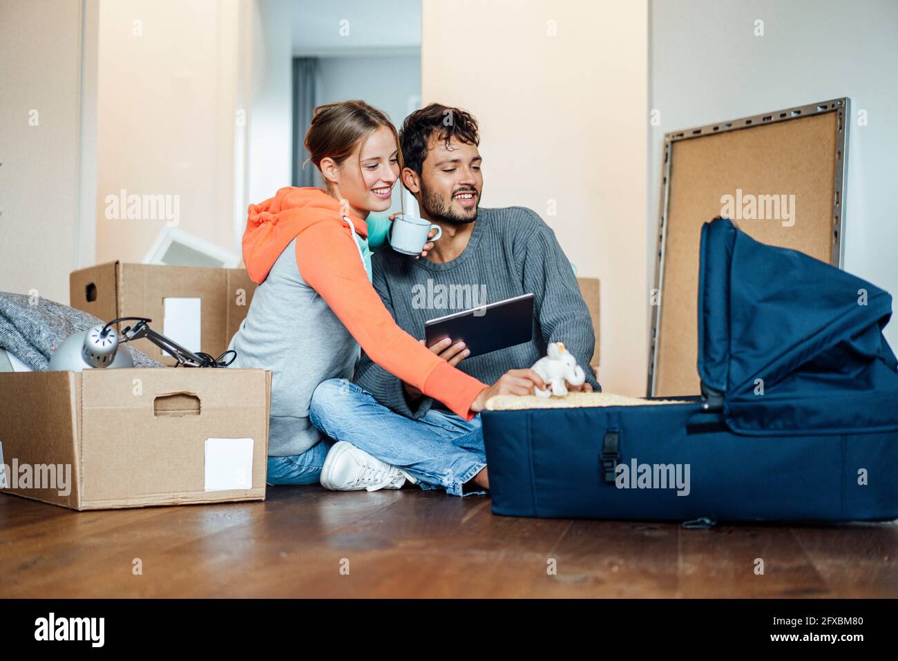 Un jeune couple souriant assis avec un porte-bébé à la maison Banque D'Images