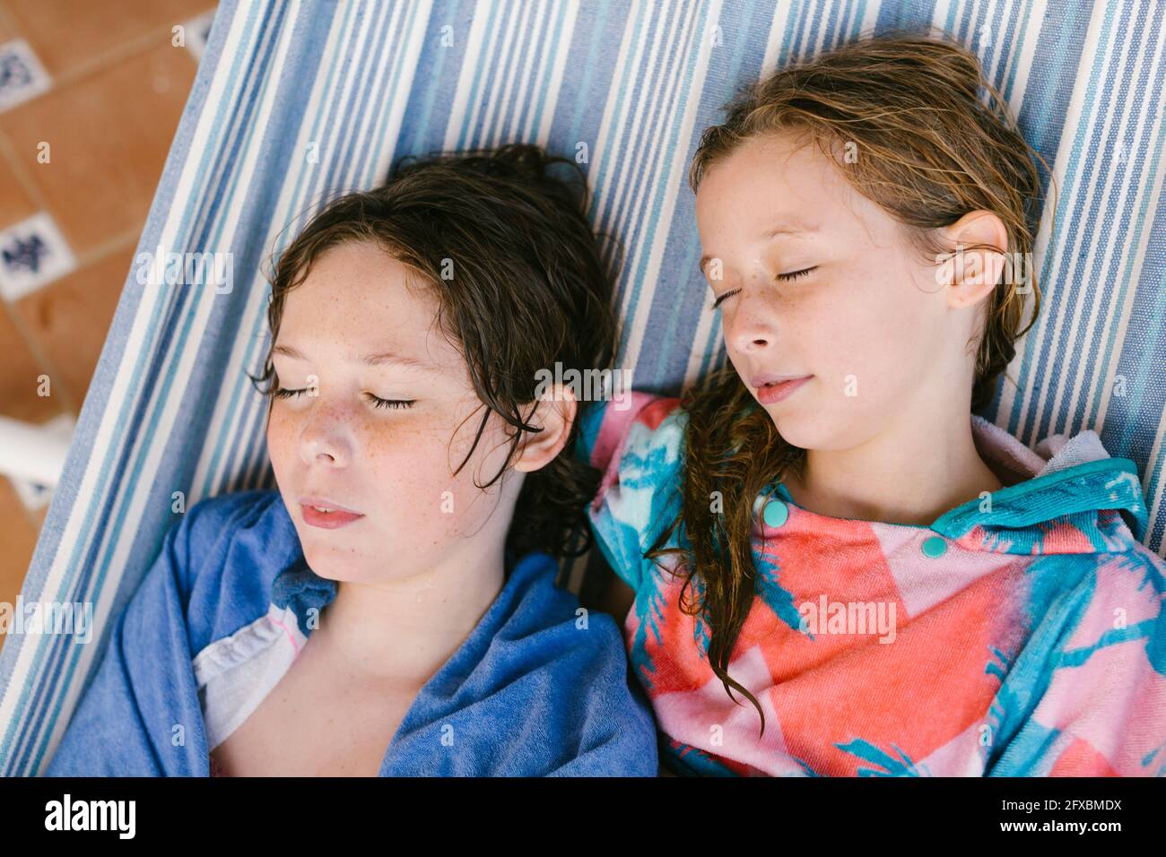 Un frère et une sœur en peignoir dormant dans un hamac Banque D'Images