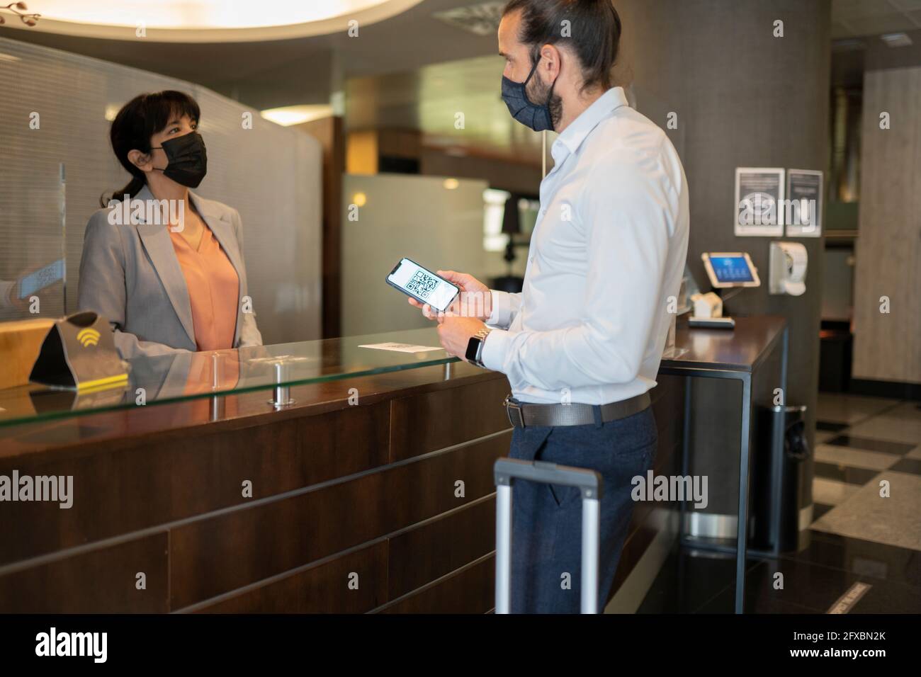 Homme mature portant un masque de protection debout au bureau de la réception Banque D'Images