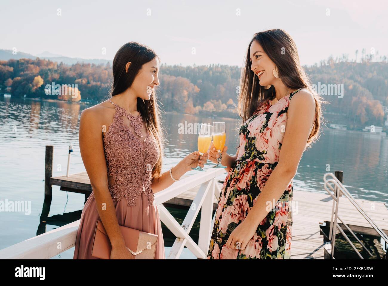 Belles femmes avec verres sur la jetée au-dessus du lac Banque D'Images