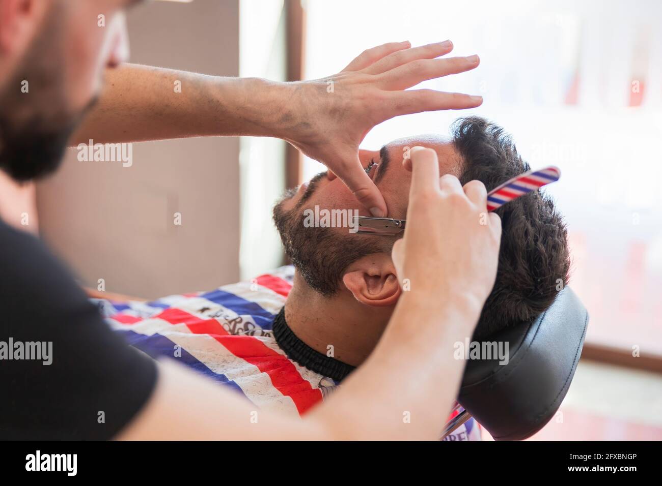 Coiffeur masculin taille de la barbe de l'homme avec un rasoir au salon Banque D'Images