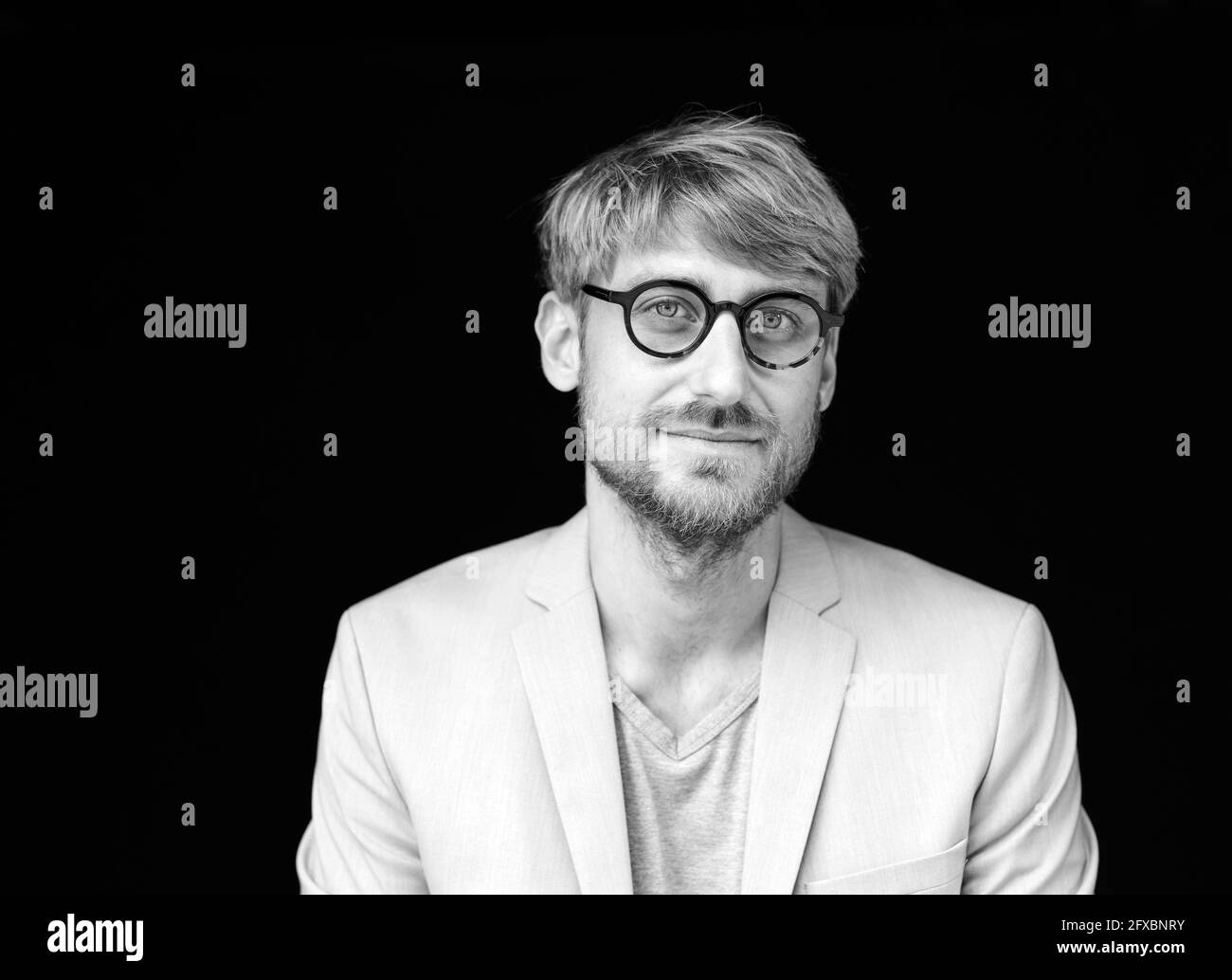 Homme portant des lunettes devant un arrière-plan noir Banque D'Images