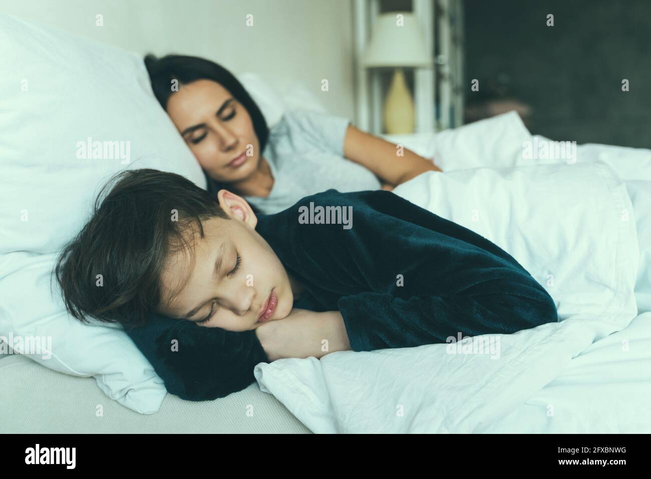 Fils dormant avec mère sur le lit à la maison Banque D'Images