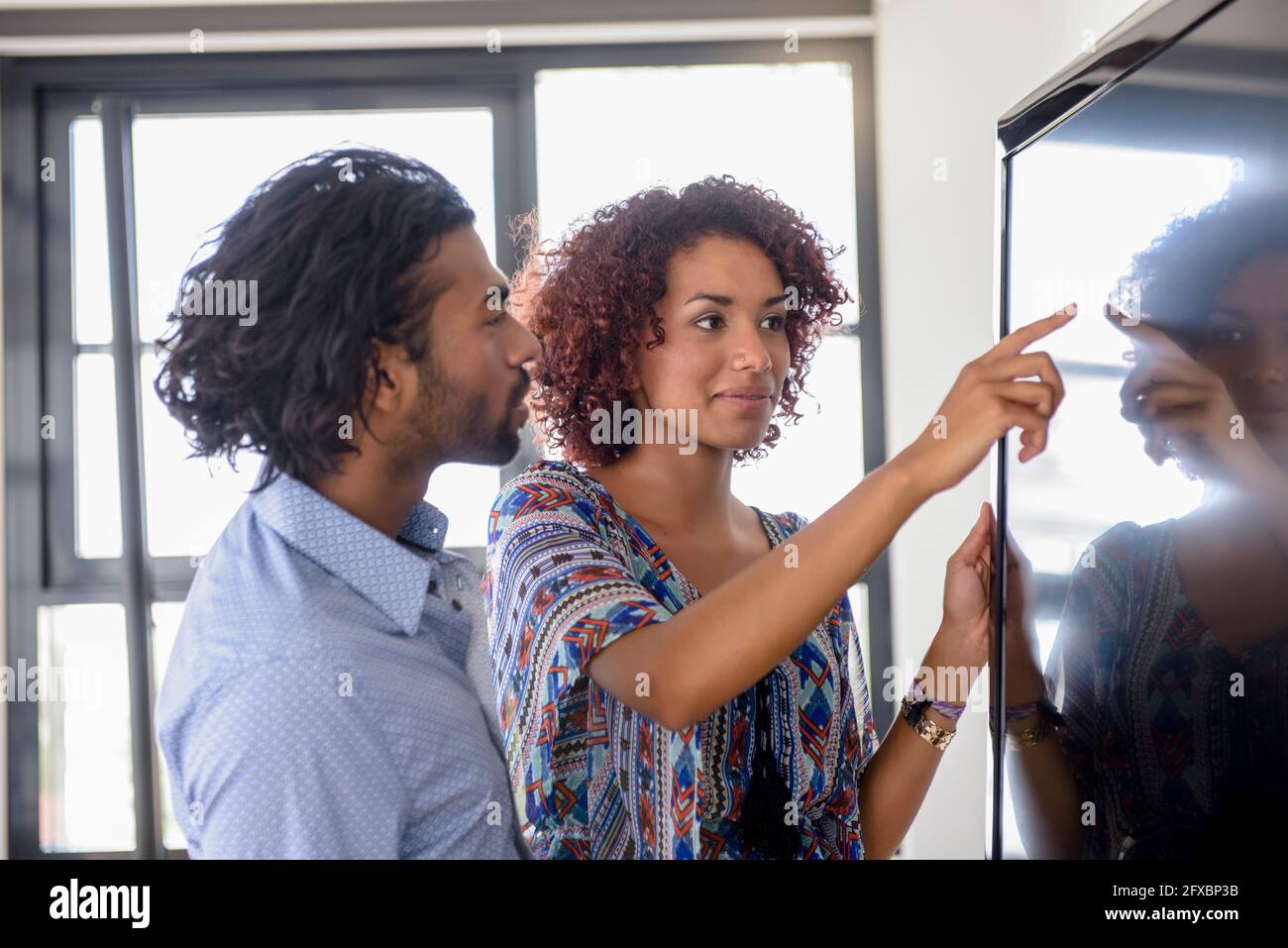 Femme entrepreneur remue-méninges avec un collègue sur écran numérique au bureau Banque D'Images