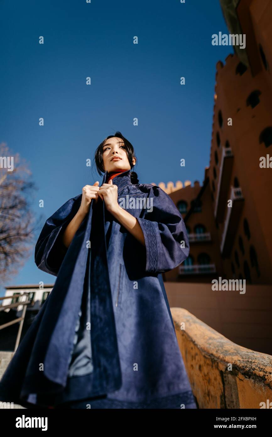 Jeune femme portant un manteau regardant loin pendant la journée ensoleillée Banque D'Images
