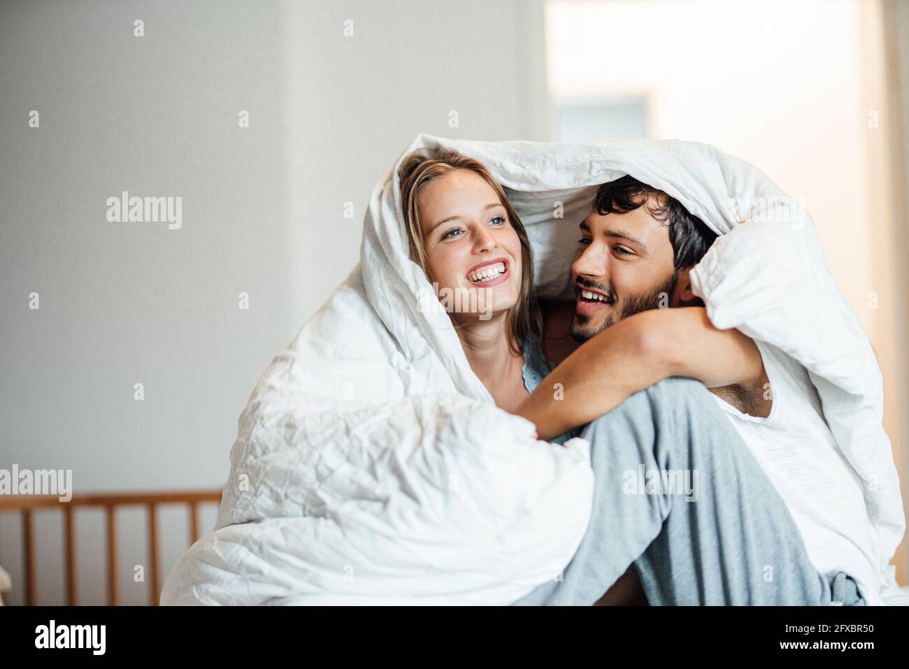 Couple heureux assis sous une couverture à la maison Photo Stock - Alamy