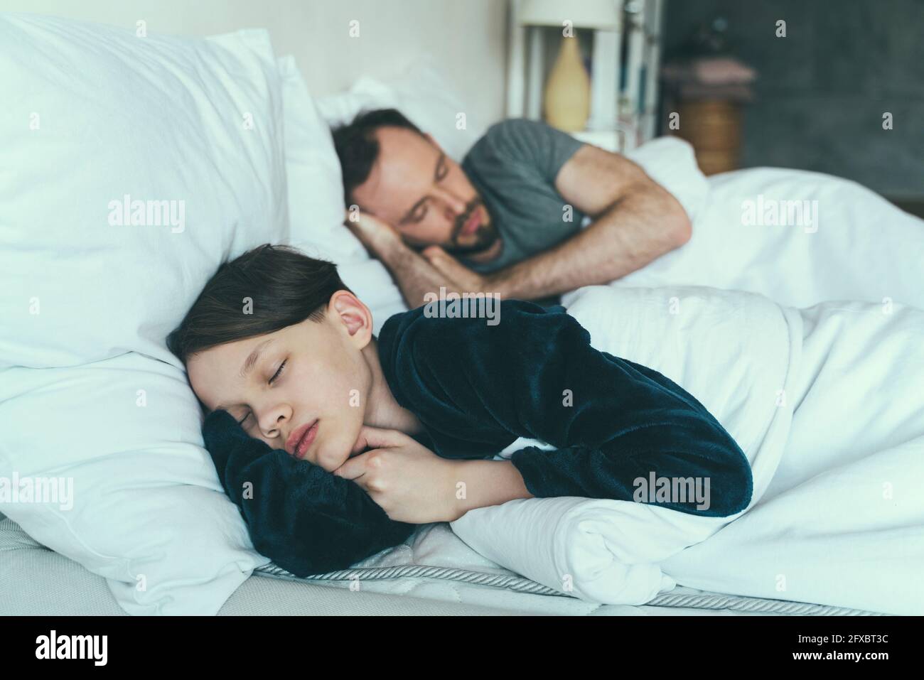 Fils dormant avec père sur le lit à la maison Banque D'Images