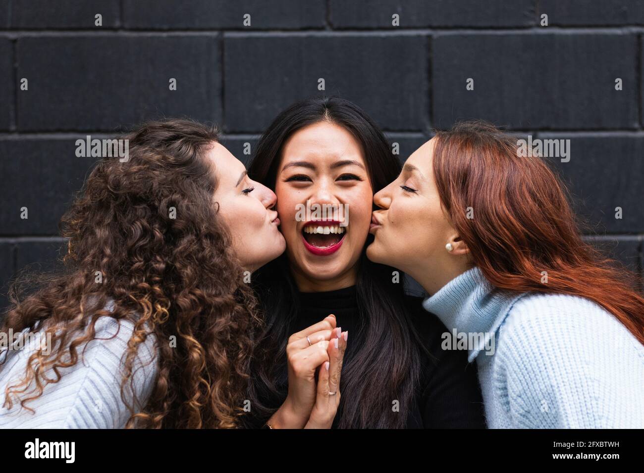 Des amies embrassant une femme joyeuse Banque D'Images