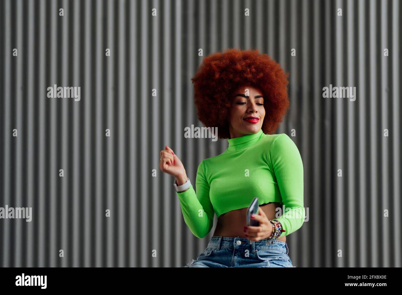 Femme en crop top dansant devant le mur gris Banque D'Images
