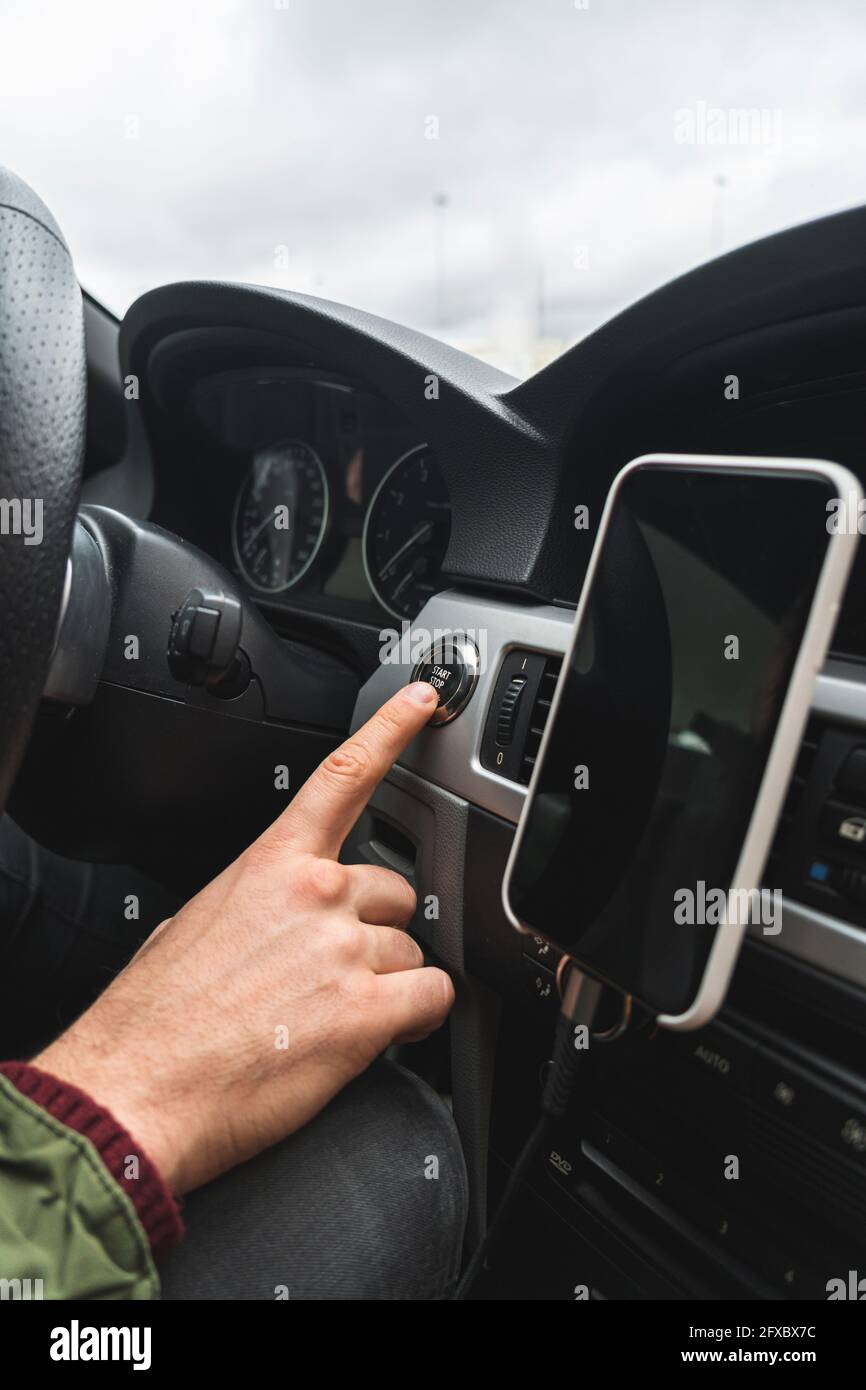 Homme appuyant sur le bouton de démarrage dans la voiture Banque D'Images