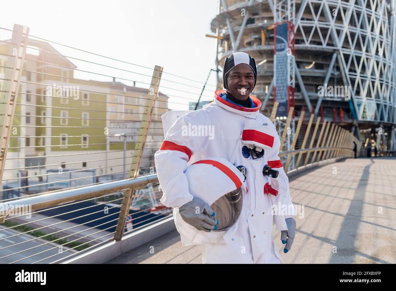 Un astronaute souriant tenant un casque d'espace debout sur le pont en ville Banque D'Images