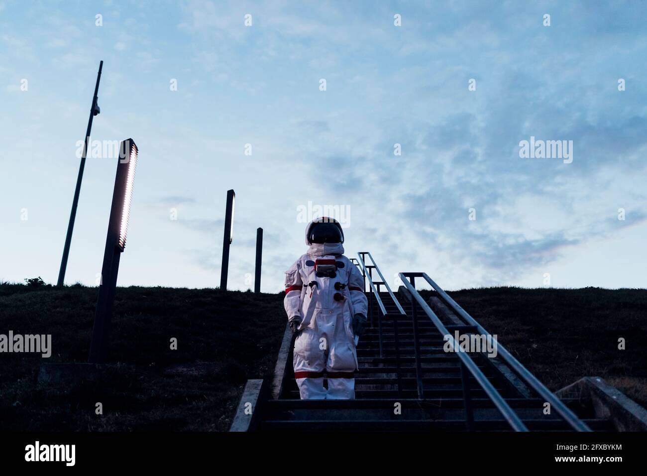 Femme astronaute debout sur les marches du parc pendant la nuit Banque D'Images