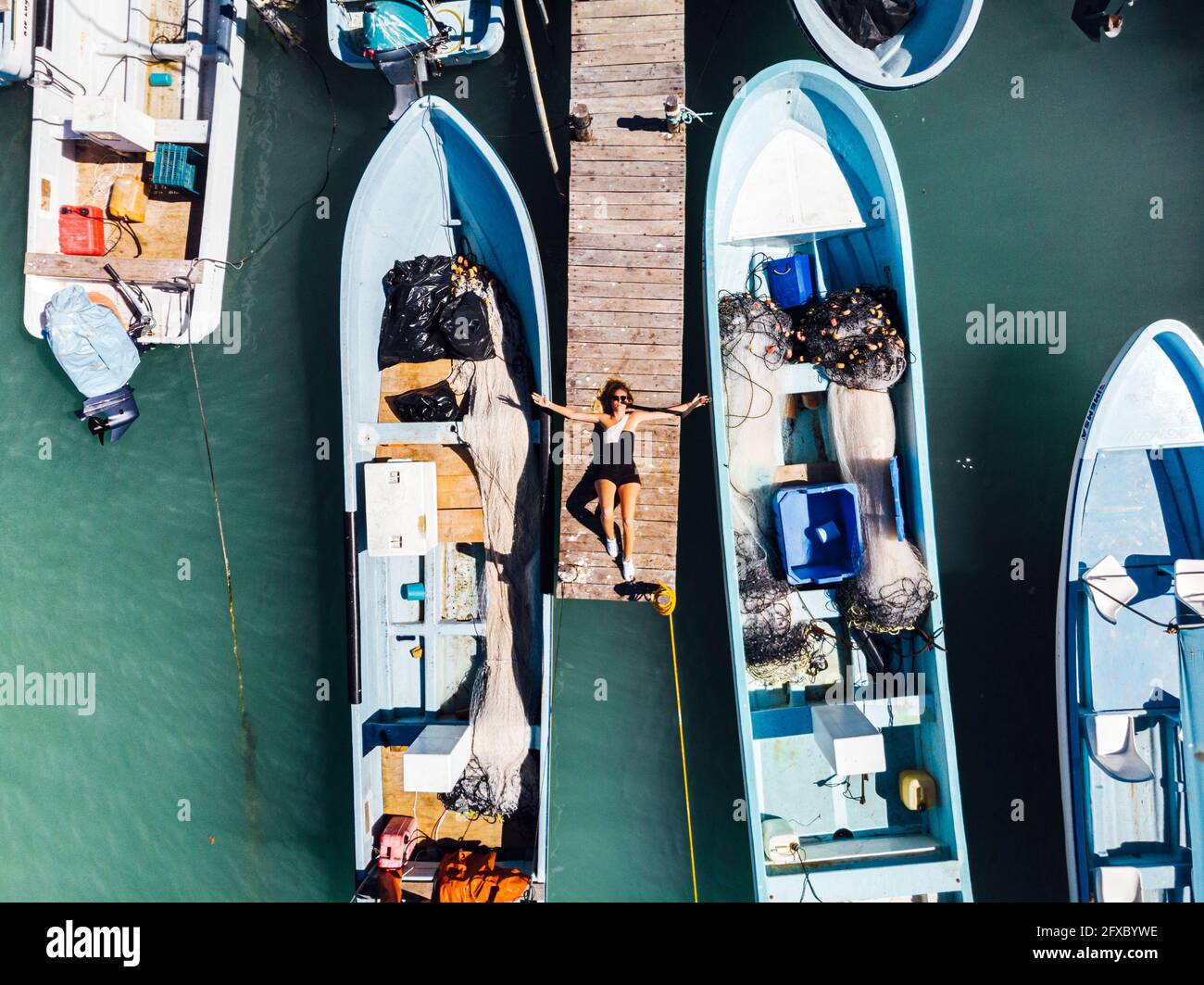 Femme couché sur la jetée au milieu des bateaux à Rio Lagartos, Yucatan, Mexique Banque D'Images