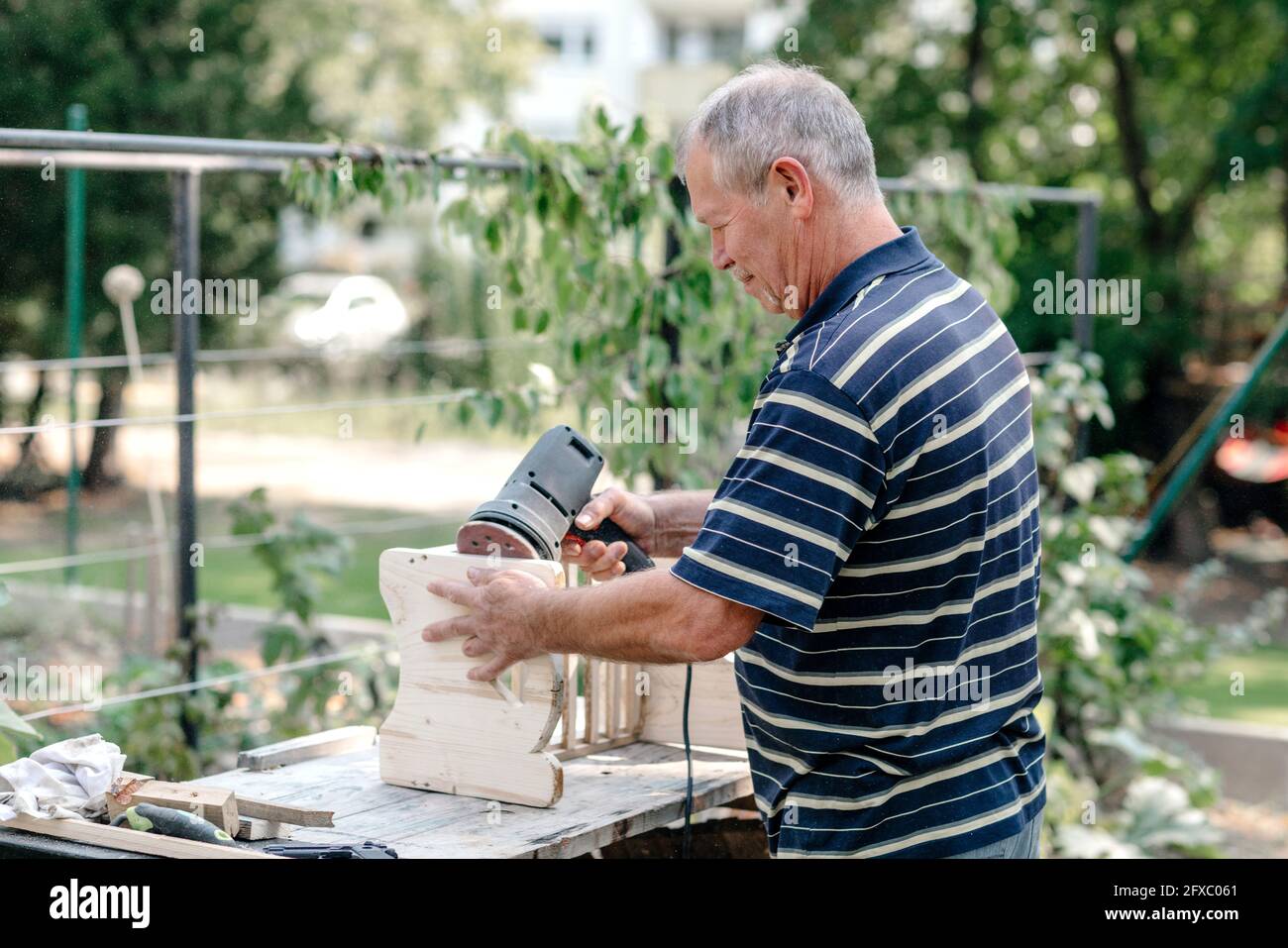 Homme senior actif avec outil de travail du bois faisant la menuiserie dans l'arrière-cour Banque D'Images