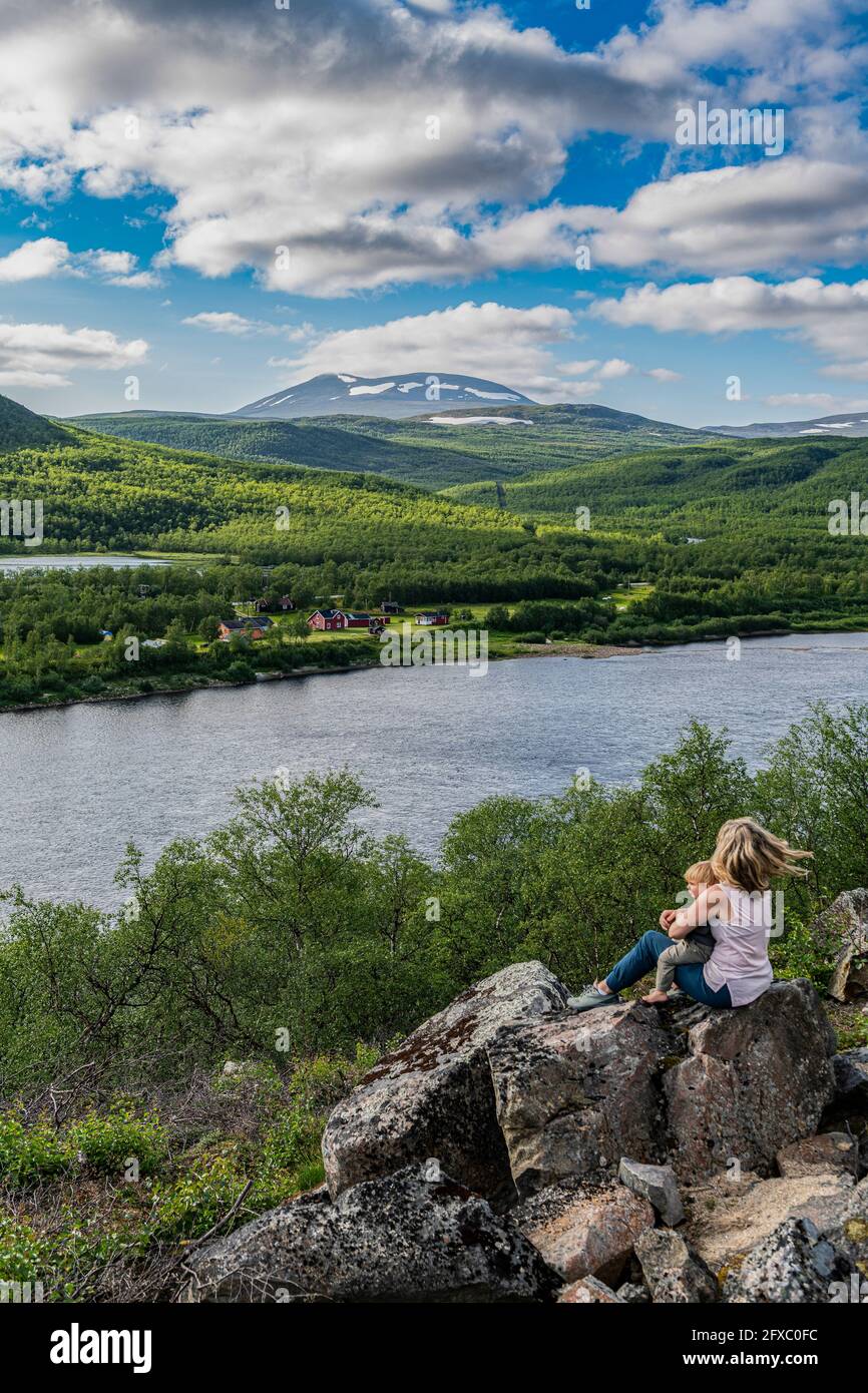 Mère et bébé fils en admirant la vue sur la rivière Karasjohka tout en étant assis au sommet d'un rocher Banque D'Images