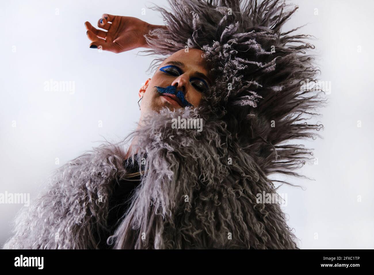 Jeune homme modèle de mode avec les yeux fermés sur fond blanc Banque D'Images
