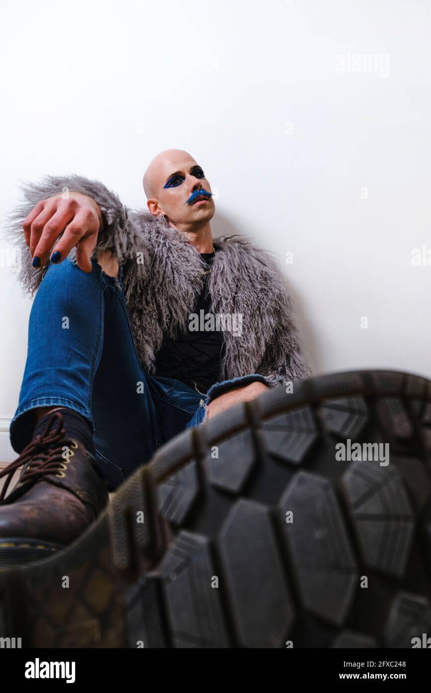Jeune mannequin de mode masculin assis sur fond blanc Banque D'Images