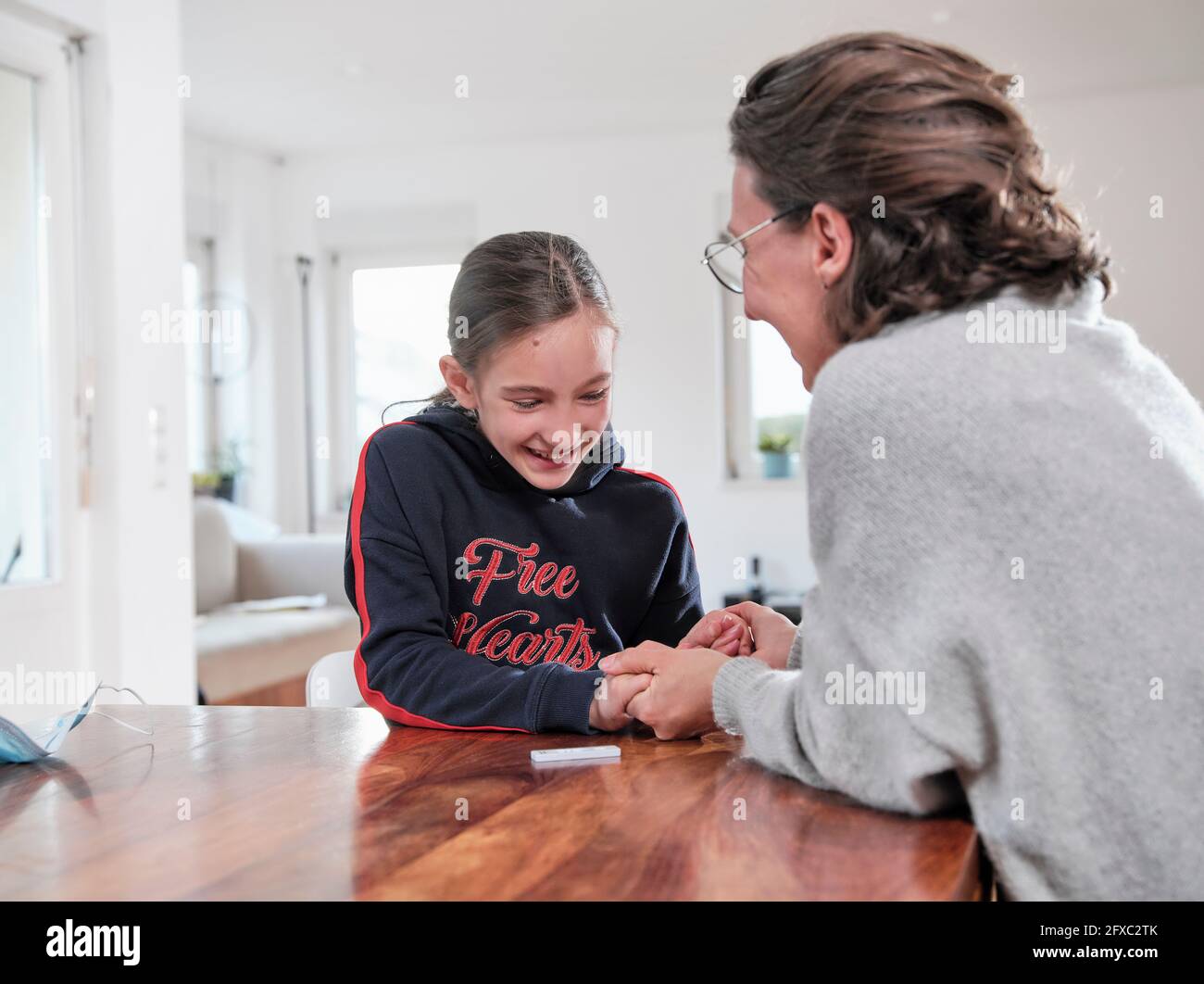 Bonne mère et fille se tenant les mains tout en faisant le test COVID-19 à la maison Banque D'Images