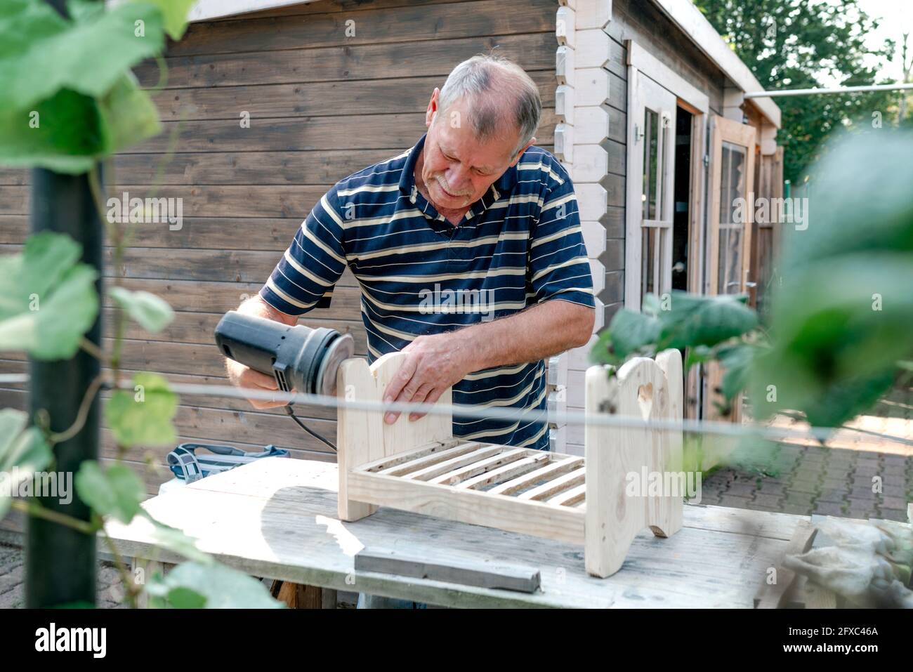 Homme senior avec outil de travail du bois faisant la menuiserie à l'arrière-cour Banque D'Images
