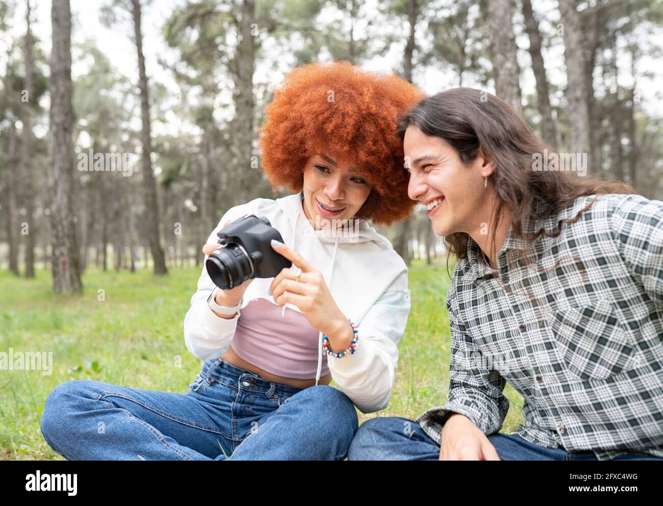 Femme souriante montrant un appareil photo à un ami pendant une fête dans la forêt Banque D'Images
