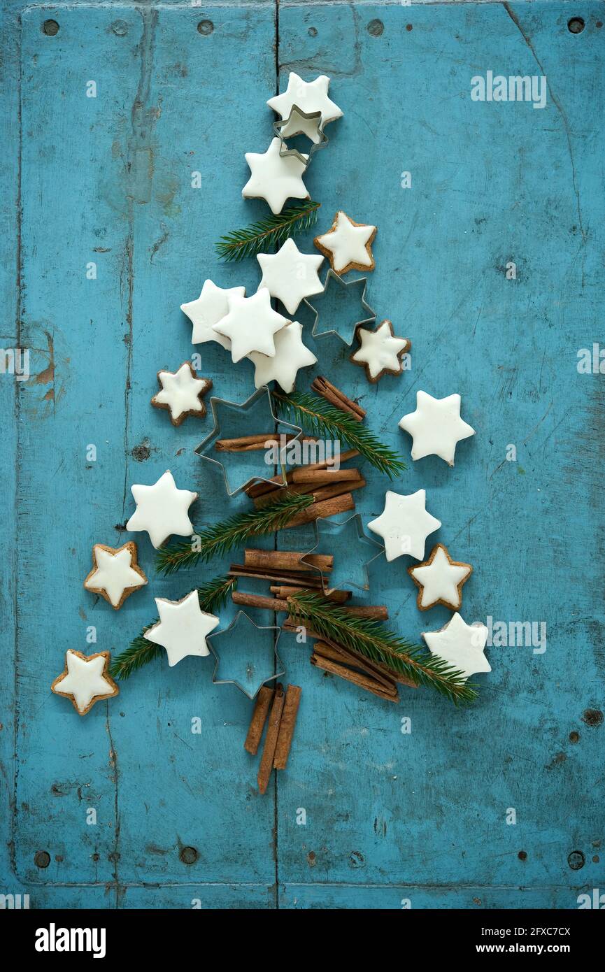Biscuits en forme d'étoile à la cannelle de Noël avec branches de cannelle et d'aiguille disposés dans le sapin de Noël sur fond de bois rustique bleu Banque D'Images