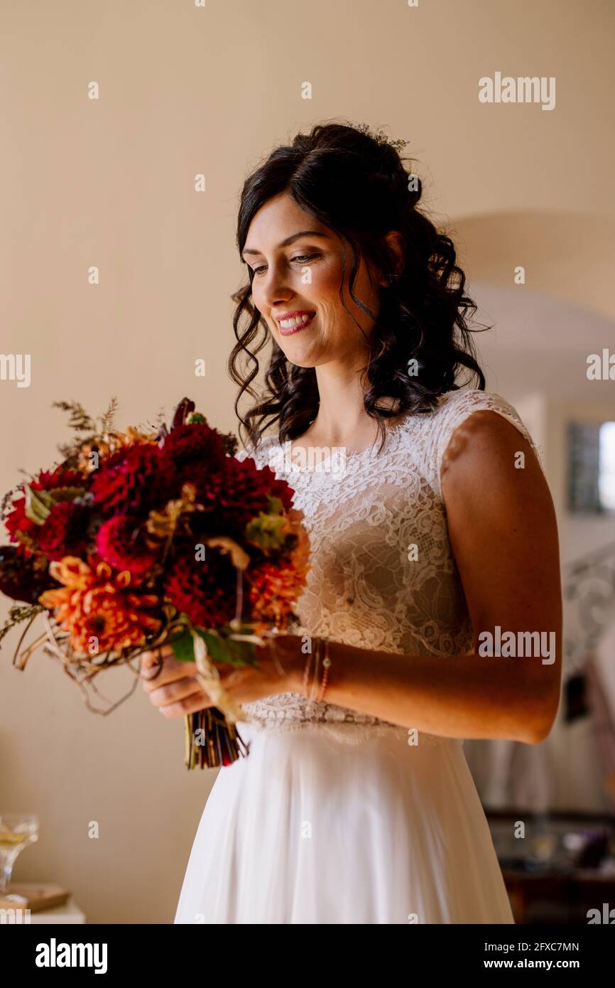 Belle mariée tenant bouquet dans la chambre domestique Banque D'Images