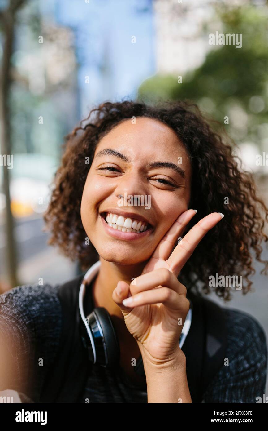 Femme joyeuse montrant le signe de la paix dans la ville Banque D'Images