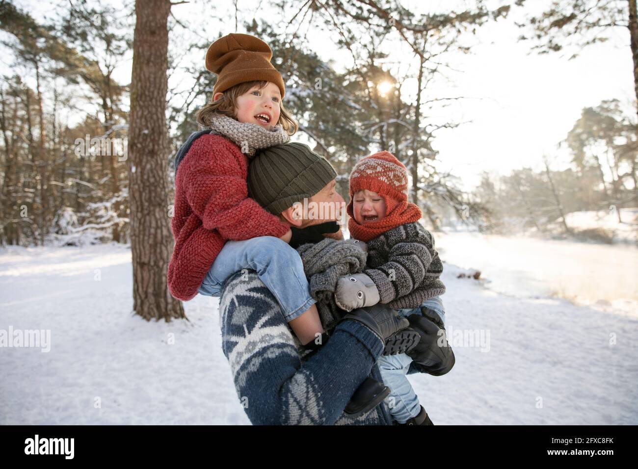 Père portant un garçon sur l'épaule tout en regardant pleurer son pendant l'hiver Banque D'Images