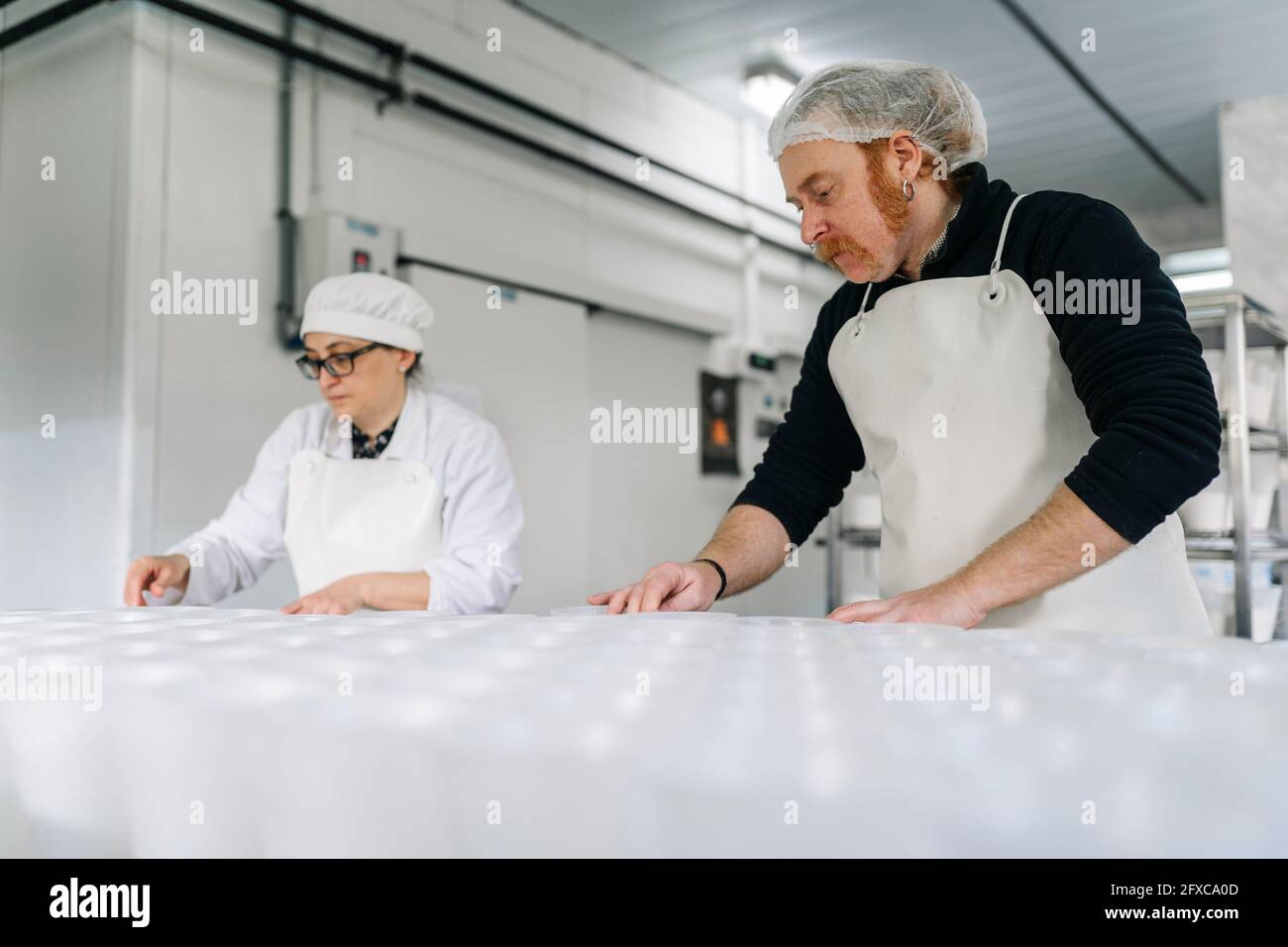 Chefs hommes et femmes travaillant dans une fromagerie Banque D'Images