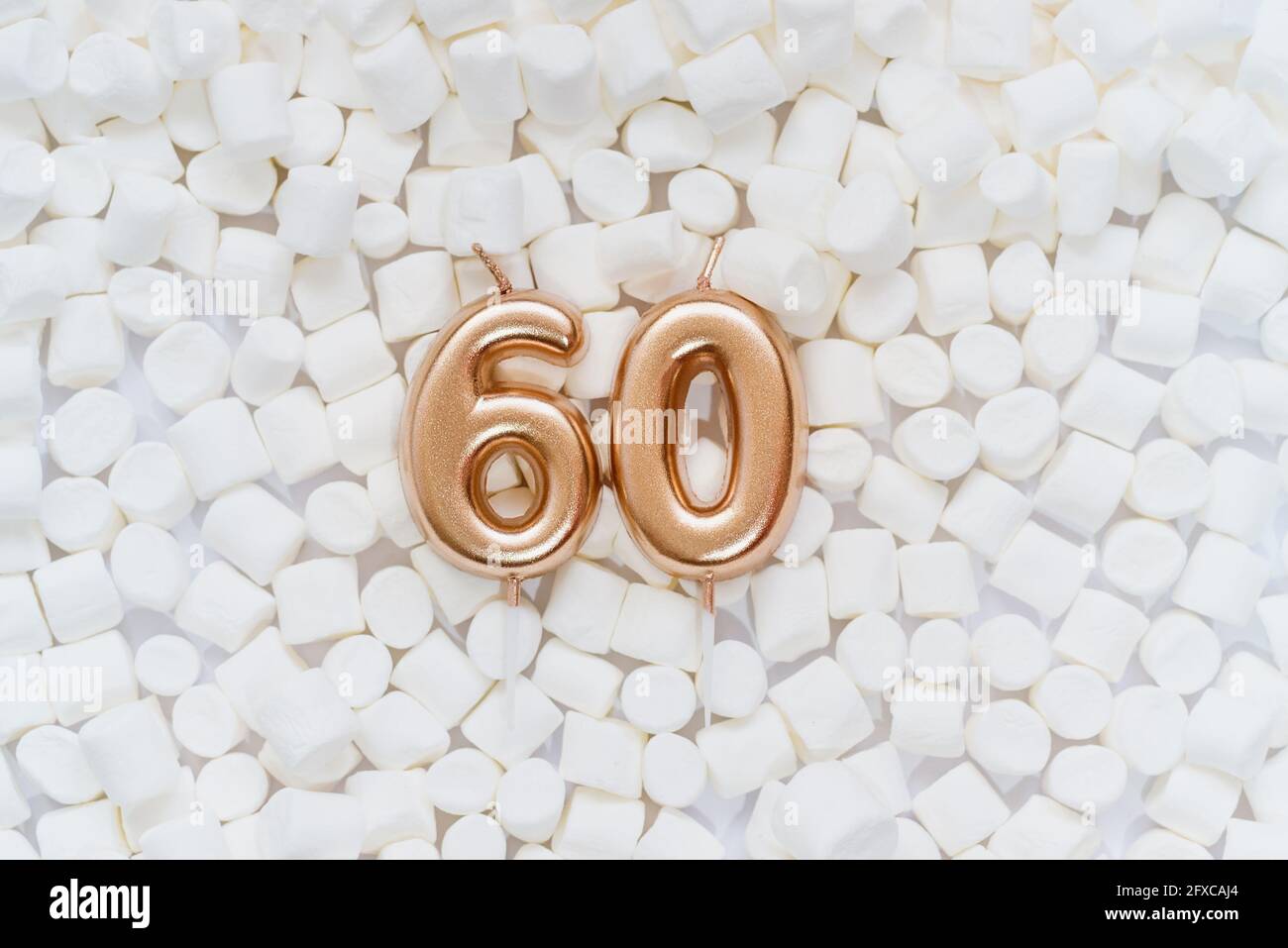 Numéro 60 bougie d'anniversaire dorée sur fond avec guimauves blanches. Anniversaire de soixante ans. Concept de célébration d'anniversaire, anniversaire Banque D'Images
