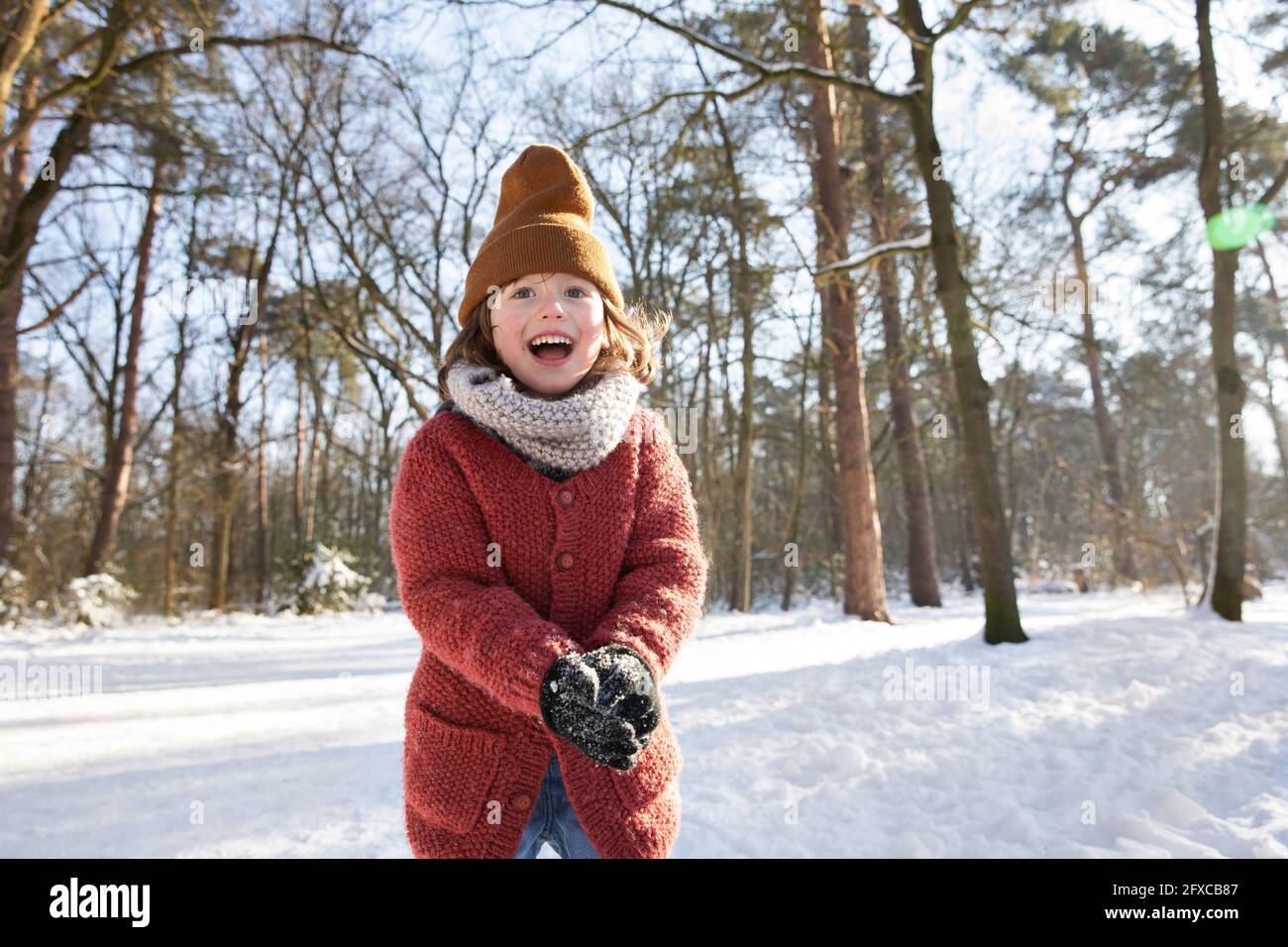 Curieux garçon dans des vêtements chauds jouant avec la neige pendant l'hiver Banque D'Images