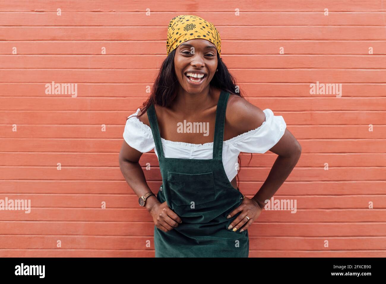 Femme gaie avec main sur la hanche par mur Banque D'Images