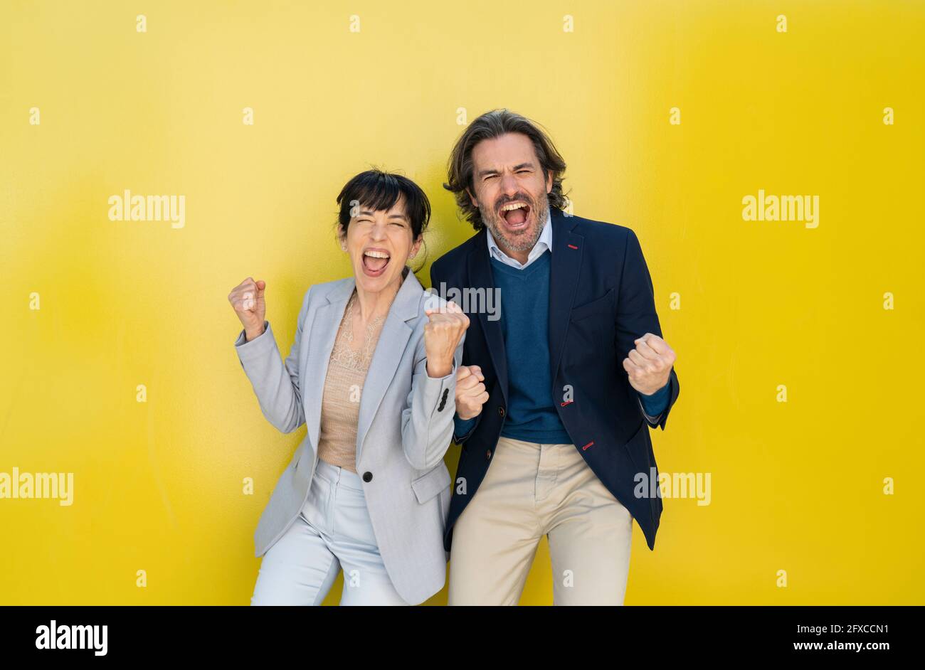 Un couple d'affaires applaudisse en se tenant devant le mur Banque D'Images