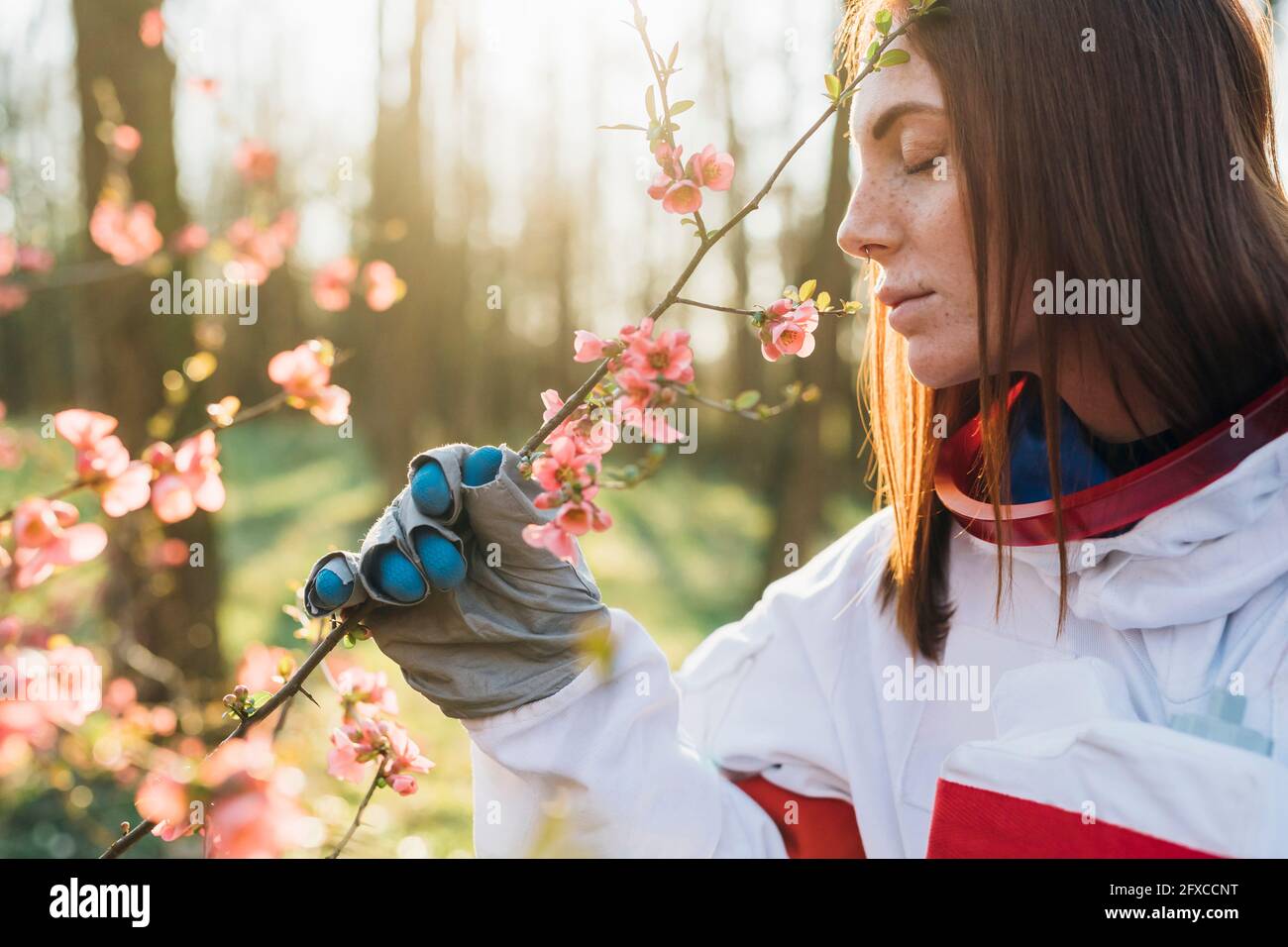 Jeune explorateur féminin avec des taches de rousseur qui sentent la fleur dans la forêt Banque D'Images