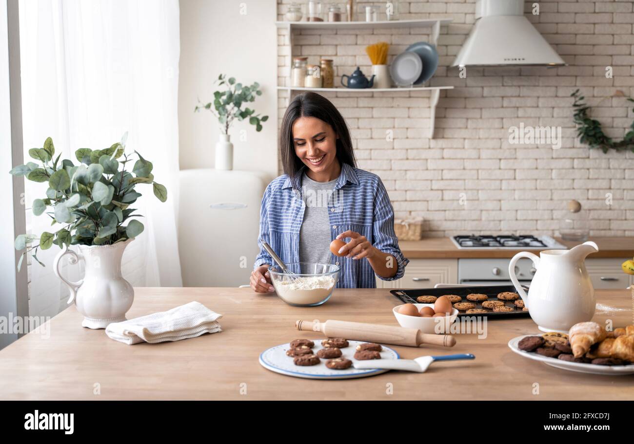 Femme tenant l'œuf tout en préparant la nourriture dans la cuisine à la maison Banque D'Images