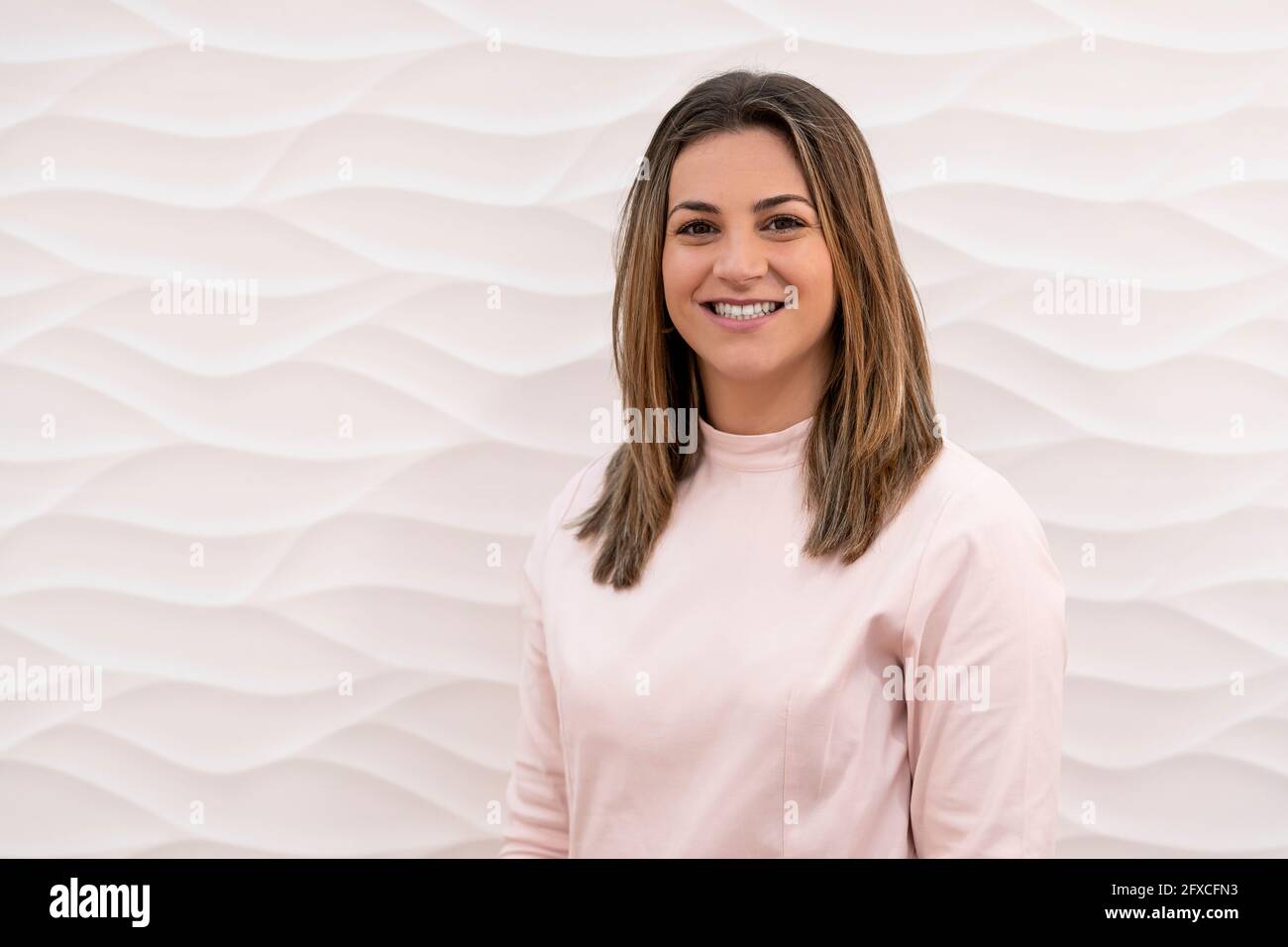 Femme souriante debout devant le mur blanc à la clinique Banque D'Images