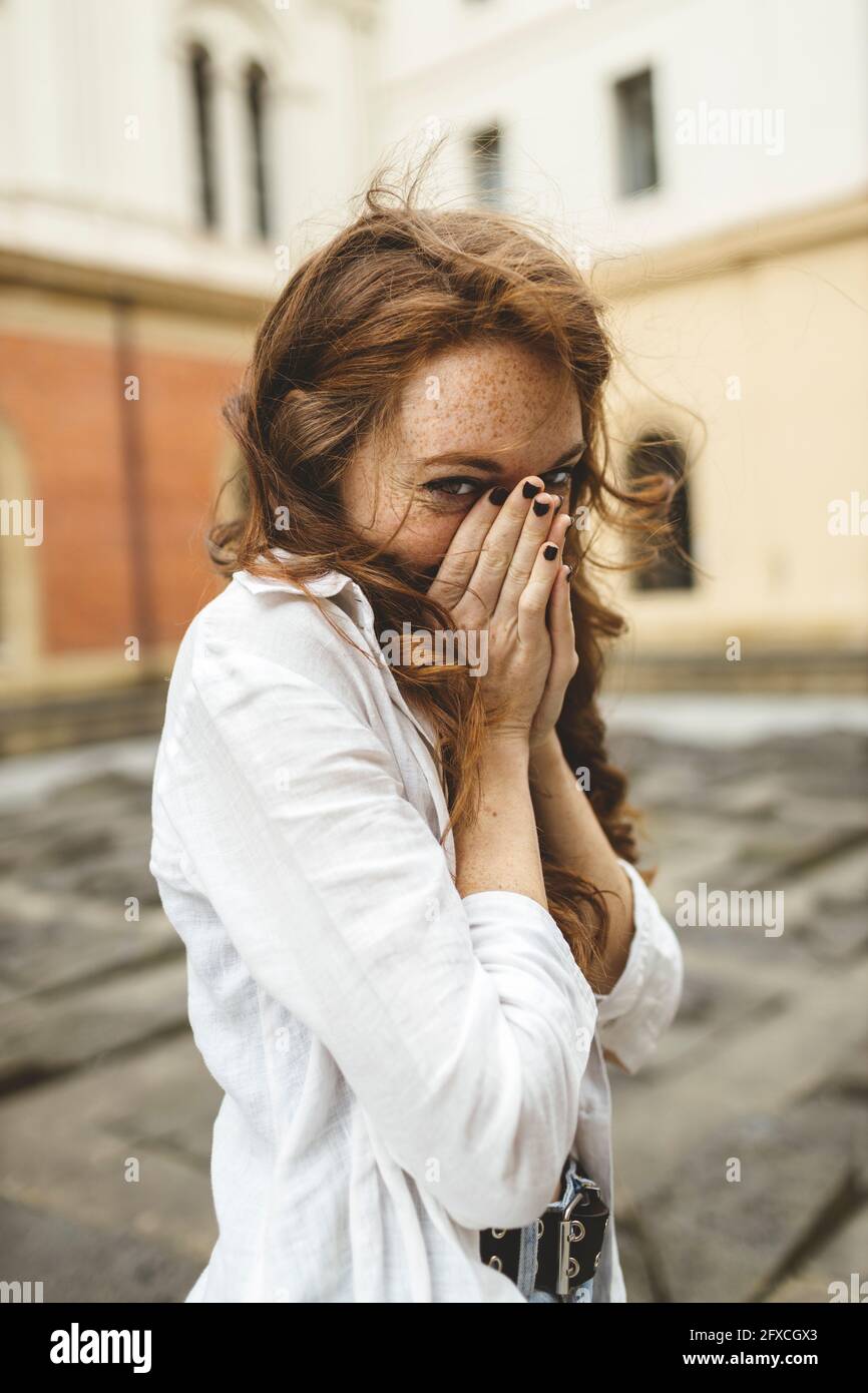 Jeune femme regardant tout en couvrant la bouche avec les mains Banque D'Images