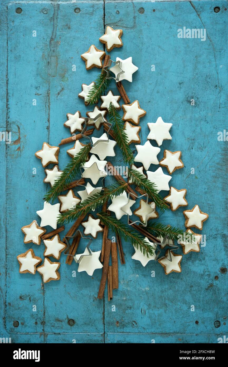 Biscuits en forme d'étoile à la cannelle de Noël avec branches de cannelle et d'aiguille disposés dans le sapin de Noël sur fond de bois rustique bleu Banque D'Images