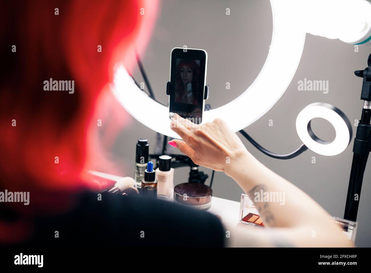 Vlogger femelle utilisant un téléphone portable connecté à la sonnerie lumière dans le studio Banque D'Images