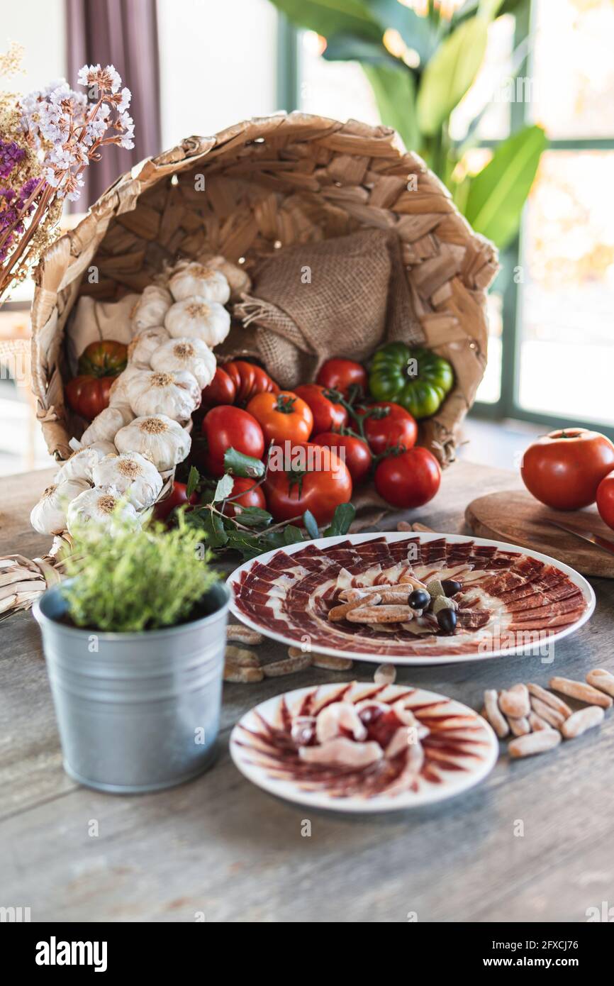 Tranches de jambon serrano dans l'assiette par panier de légumes au restaurant Banque D'Images