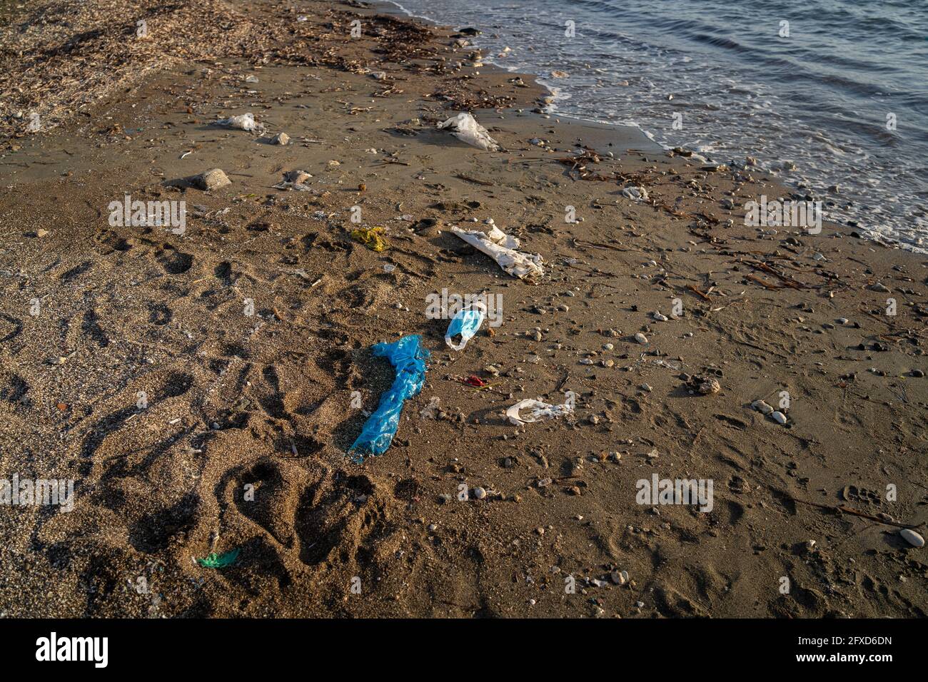 Bleu utilisé masque médical jeté sur la plage par la mer. Traitement d'objets et de déchets de fournitures médicales. Arrêter la pollution de l'eau et de l'océan. Post Covid 19 Banque D'Images