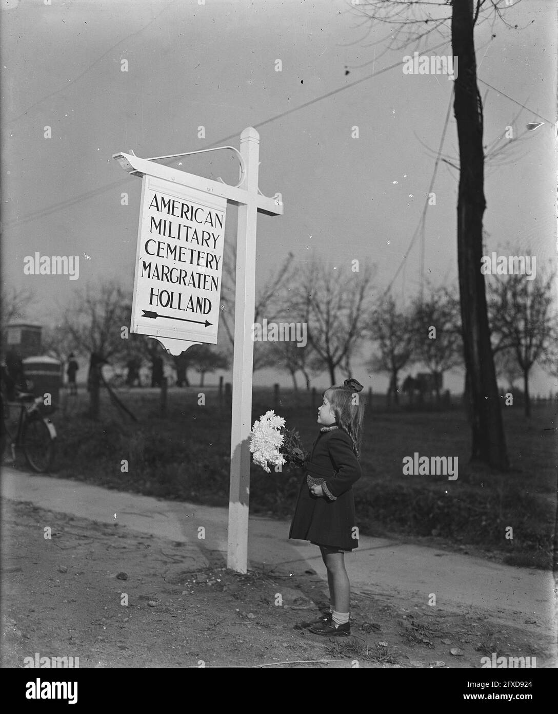 Petite fille avec des fleurs au signe directionnel du cimetière américain, 12 novembre 1945, cimetières, armées, Pays-Bas, Agence de presse du XXe siècle photo, nouvelles à retenir, documentaire, photographie historique 1945-1990, histoires visuelles, L'histoire humaine du XXe siècle, immortaliser des moments dans le temps Banque D'Images