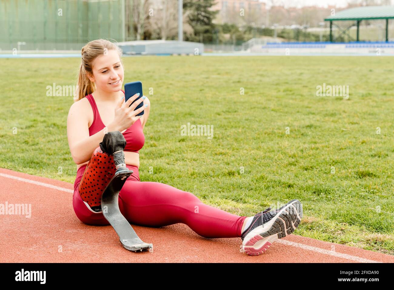 Sportswoman avec handicap en utilisant un smartphone pendant l'entraînement Banque D'Images