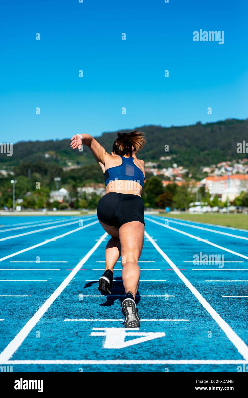 Dos de femme sprinter sur un circuit d'athlétisme Banque D'Images