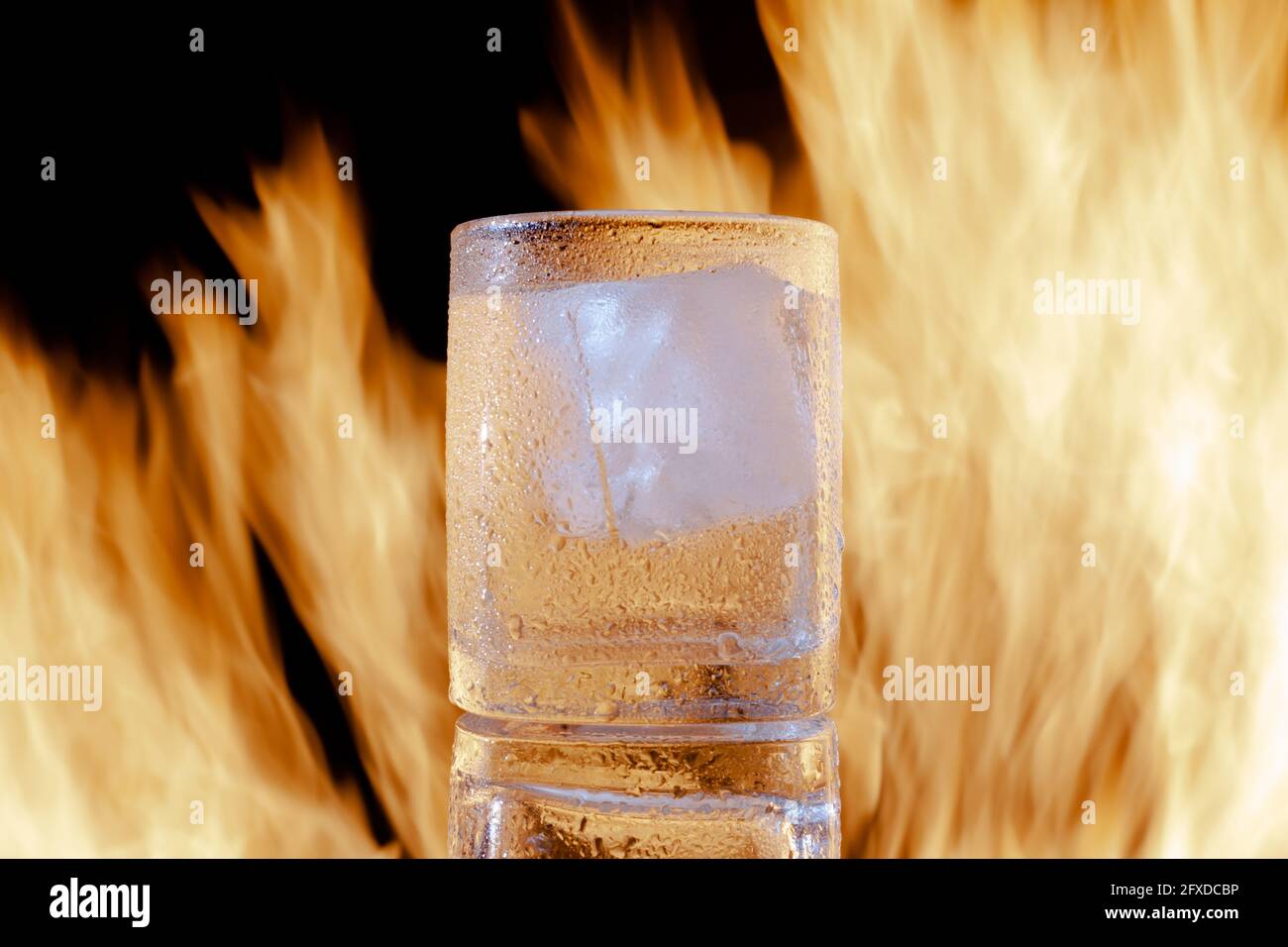 verre de brandy avec glace sur feu sur un noir arrière-plan Banque D'Images