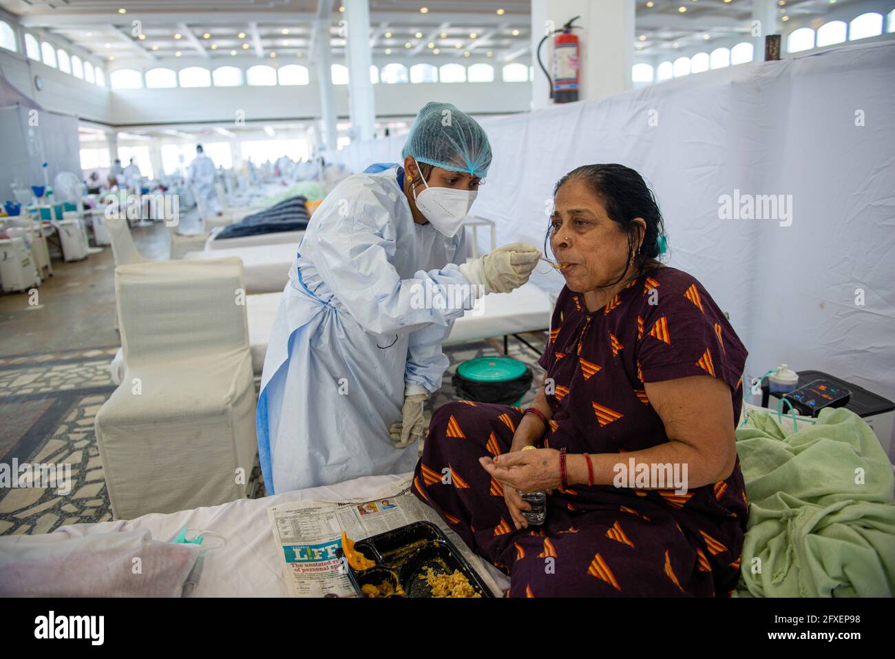 New Delhi, Inde. 26 mai 2021. Un agent de santé qui nourrit une femme avec une cuillère au Sri Guru Tegh Bahadar Covid-19 Medical isolation & Treatment Centre, à Gurdwara Rakab Ganj Sahib. Delhi Sikh Gurdwara Comité de gestion dirigez un centre de soins Covid-19 avec l'aide de l'organisation internationale des droits de l'homme et du gouvernement de Delhi. Le 26 mai 2021 24, 95,591 cas actifs ont été enregistrés en Inde selon le site Web du ministère de la Santé. (Photo de Pradeep Gaur/SOPA Images/Sipa USA) crédit: SIPA USA/Alay Live News Banque D'Images